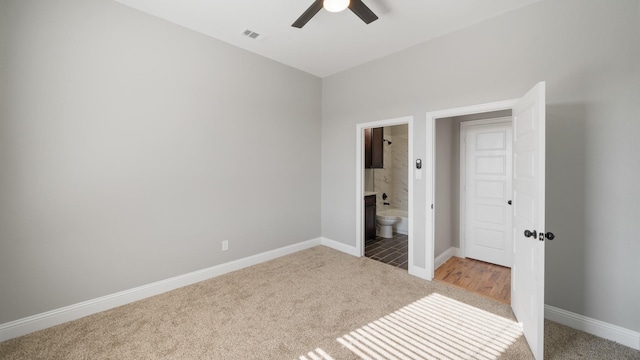 unfurnished bedroom with ceiling fan, light colored carpet, and ensuite bathroom