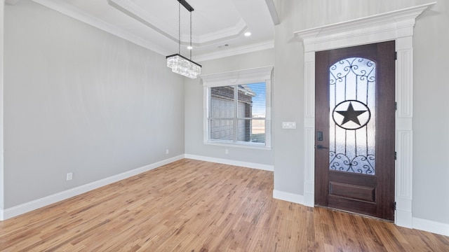 foyer featuring crown molding, a raised ceiling, and light hardwood / wood-style flooring