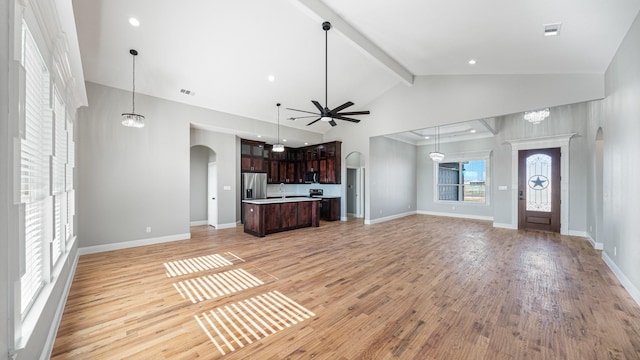 unfurnished living room with ceiling fan with notable chandelier, light hardwood / wood-style flooring, high vaulted ceiling, and beamed ceiling