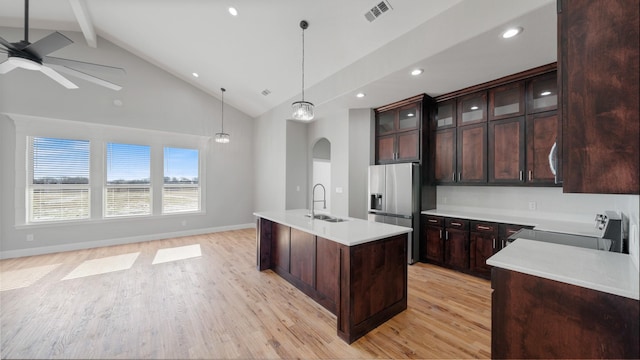 kitchen featuring pendant lighting, sink, a kitchen island with sink, range, and stainless steel refrigerator with ice dispenser