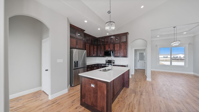 kitchen featuring sink, hanging light fixtures, stainless steel appliances, a center island with sink, and light wood-type flooring