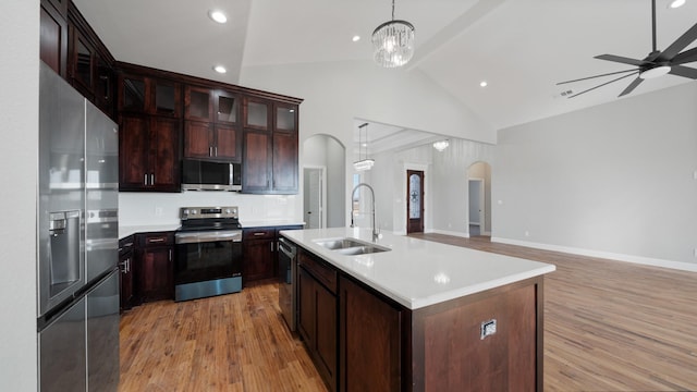 kitchen featuring sink, light hardwood / wood-style flooring, a kitchen island with sink, hanging light fixtures, and stainless steel appliances