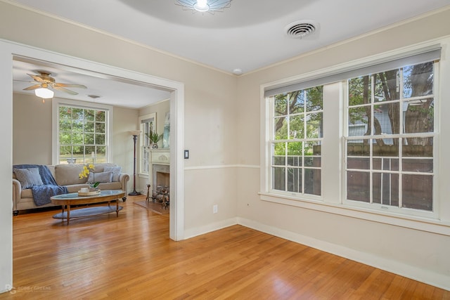 sitting room featuring ceiling fan, light wood-type flooring, and crown molding