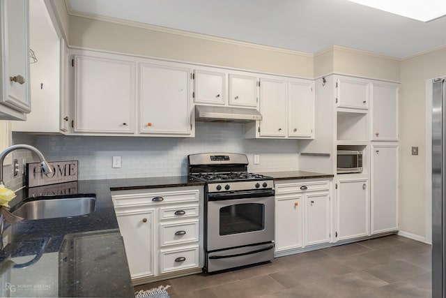 kitchen featuring decorative backsplash, stainless steel appliances, sink, dark stone countertops, and white cabinets