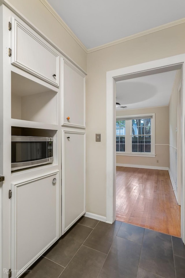 hall with dark tile patterned floors and crown molding