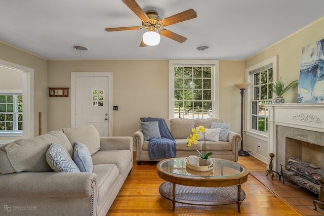 living room with ceiling fan, light wood-type flooring, and a high end fireplace