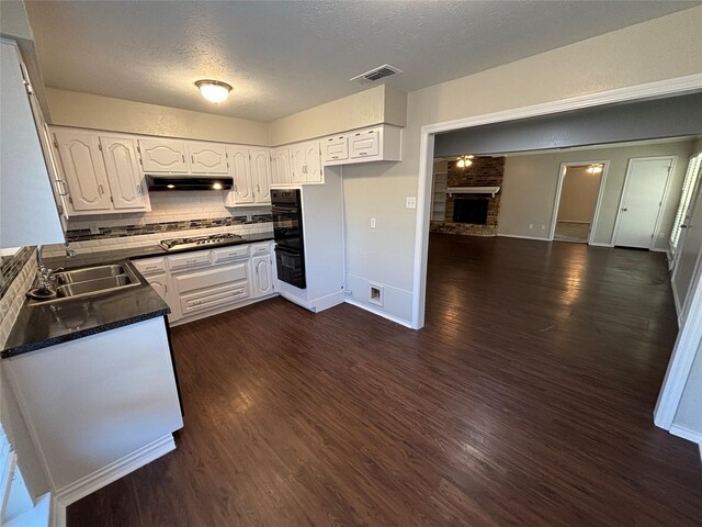 kitchen featuring white cabinetry, stainless steel gas cooktop, a fireplace, and sink