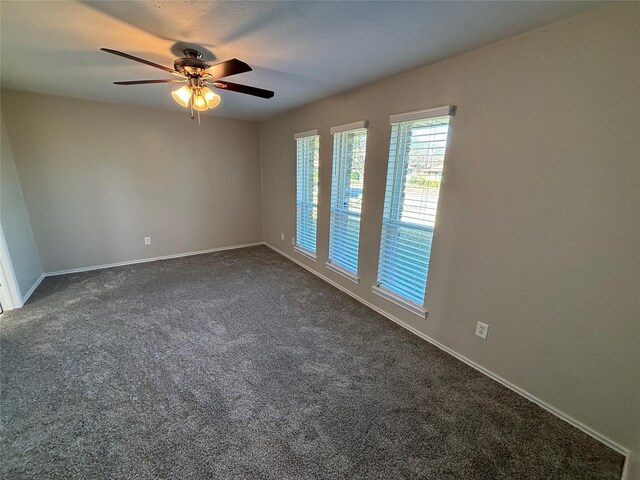 empty room featuring ceiling fan and dark colored carpet