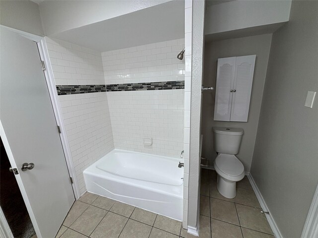 bathroom featuring tile patterned flooring, tiled shower / bath, and toilet