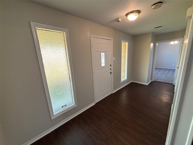 entryway with dark wood-type flooring and a textured ceiling