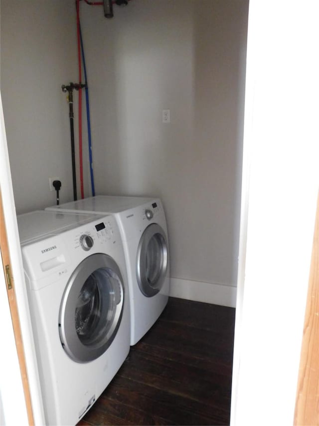 laundry room with washing machine and clothes dryer and dark wood-type flooring