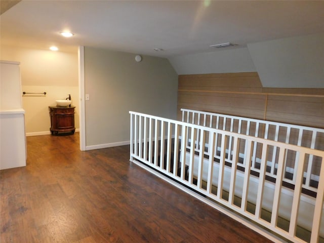 corridor with dark hardwood / wood-style floors and lofted ceiling