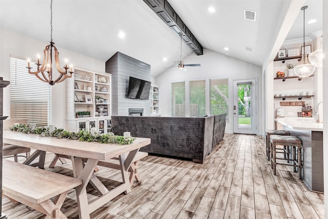 dining room featuring a large fireplace, lofted ceiling with beams, and ceiling fan with notable chandelier