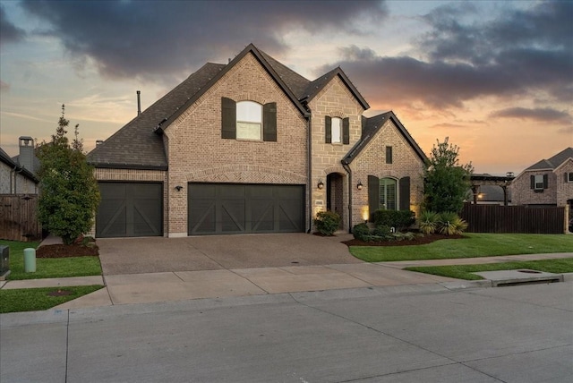 french provincial home featuring a lawn and a garage