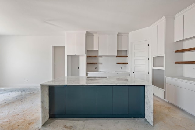 kitchen with white cabinets, a kitchen island, and light stone countertops