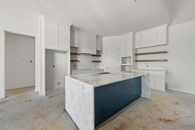 kitchen featuring a center island, white cabinetry, and light stone counters