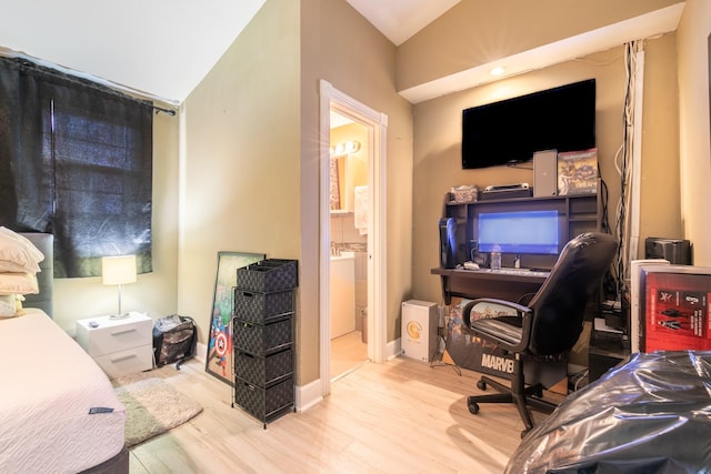 bedroom featuring ensuite bath, lofted ceiling, and light wood-type flooring