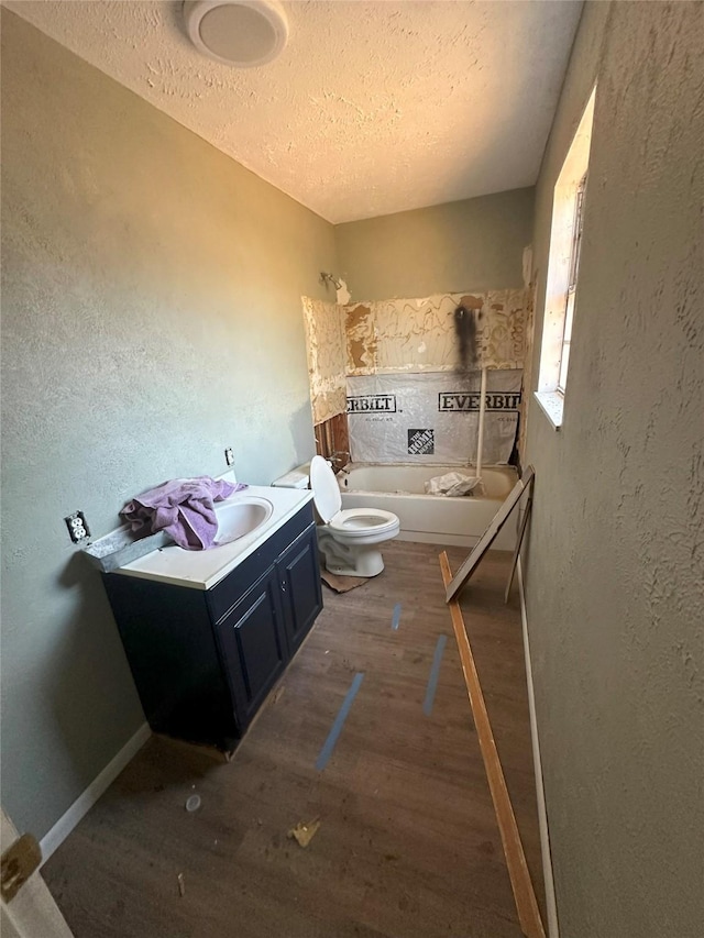 bathroom featuring a tub, wood-type flooring, a textured ceiling, toilet, and vanity