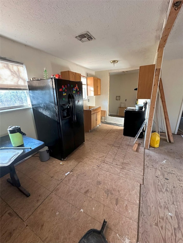 kitchen featuring black fridge and a textured ceiling