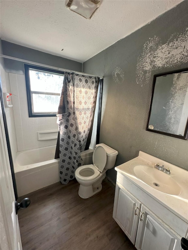 full bathroom with vanity, hardwood / wood-style flooring, toilet, shower / bath combo with shower curtain, and a textured ceiling