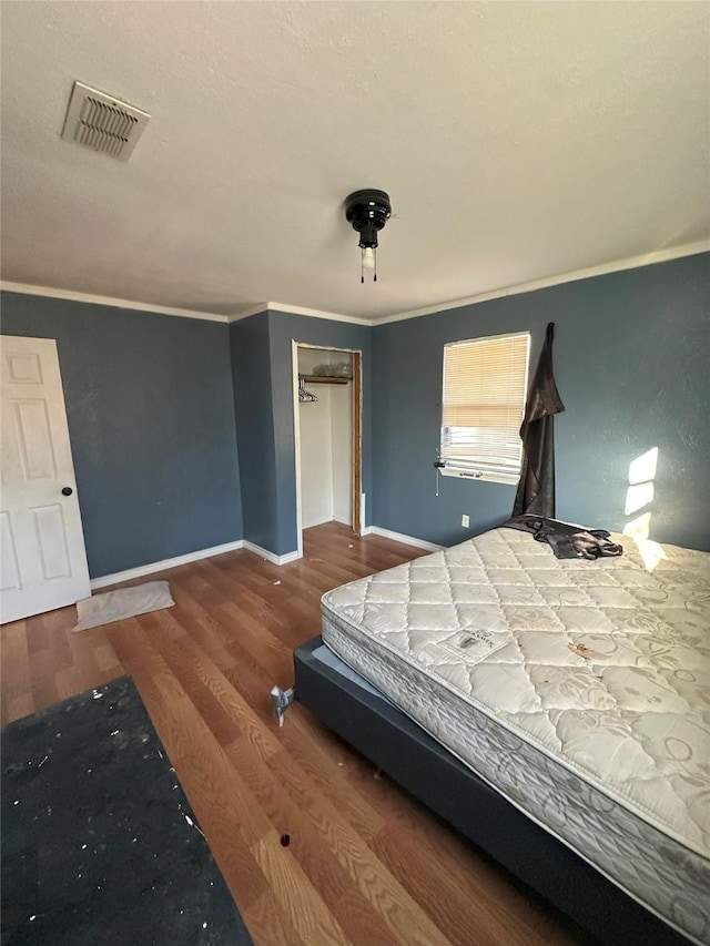 unfurnished bedroom with a closet, crown molding, and hardwood / wood-style floors