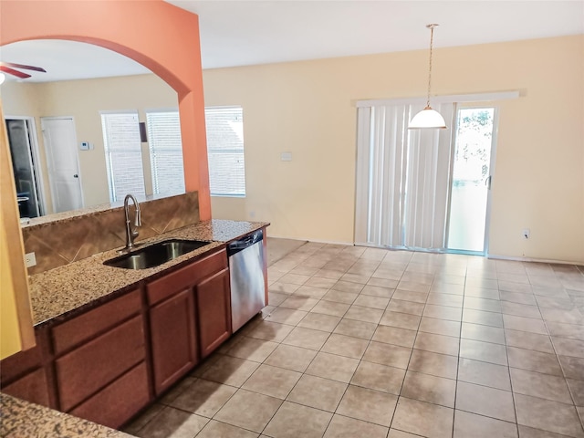 kitchen featuring light stone counters, ceiling fan, sink, dishwasher, and hanging light fixtures