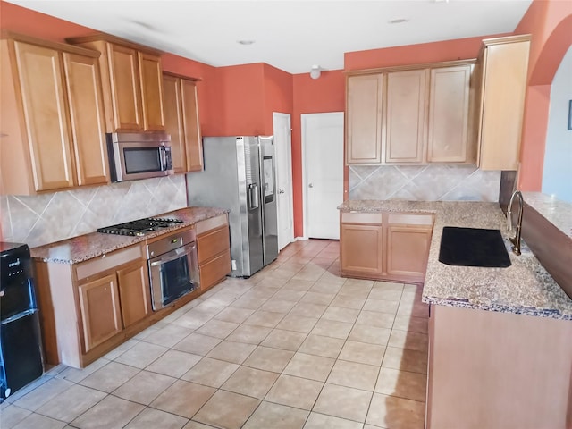 kitchen featuring sink, stainless steel appliances, tasteful backsplash, light stone counters, and light tile patterned flooring