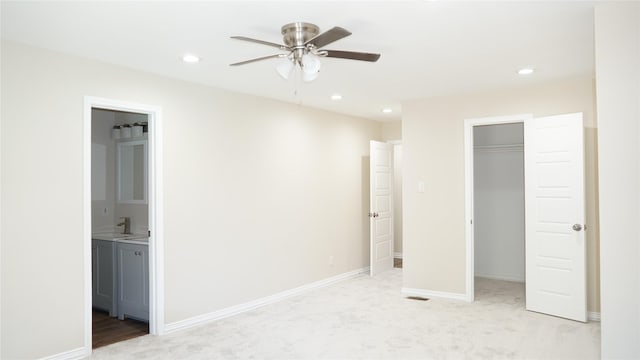 unfurnished bedroom featuring light carpet, ensuite bath, a walk in closet, and a closet