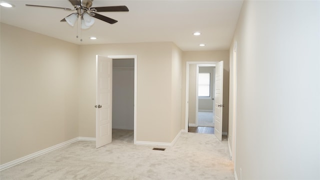 unfurnished bedroom with ceiling fan, light colored carpet, and a closet