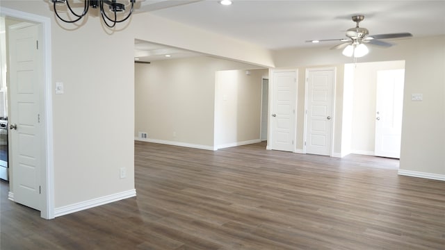 unfurnished room with ceiling fan with notable chandelier and dark wood-type flooring