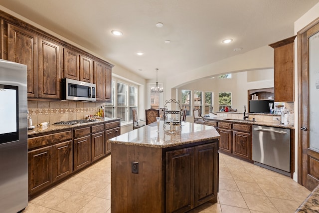 kitchen featuring sink, a center island, hanging light fixtures, stainless steel appliances, and decorative backsplash