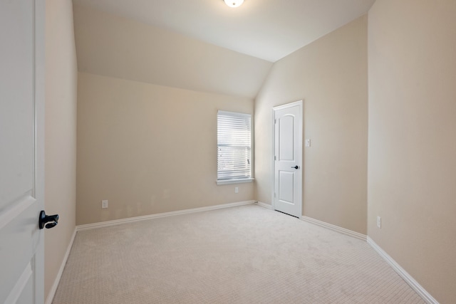 spare room with lofted ceiling and light colored carpet