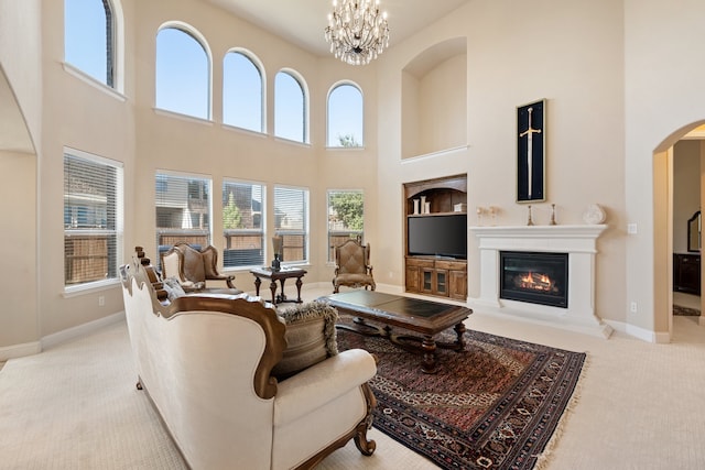 carpeted living room featuring a chandelier and a high ceiling