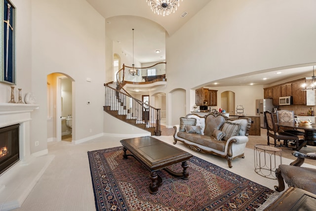 living room with a notable chandelier, light colored carpet, and a high ceiling