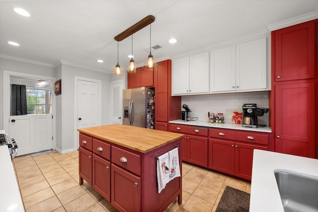 kitchen with stainless steel fridge with ice dispenser, hanging light fixtures, light tile patterned floors, ornamental molding, and backsplash