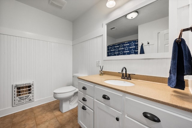 bathroom featuring tile patterned floors, toilet, heating unit, and vanity