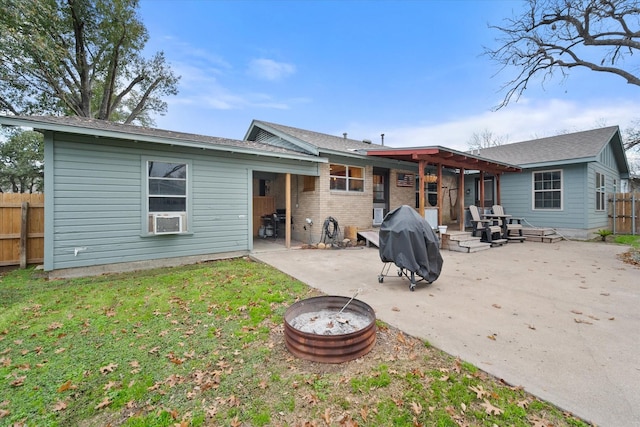 back of house featuring a patio, a lawn, and a fire pit