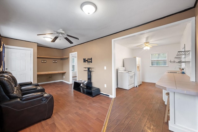 living room featuring ceiling fan, washer / clothes dryer, sink, and light hardwood / wood-style flooring