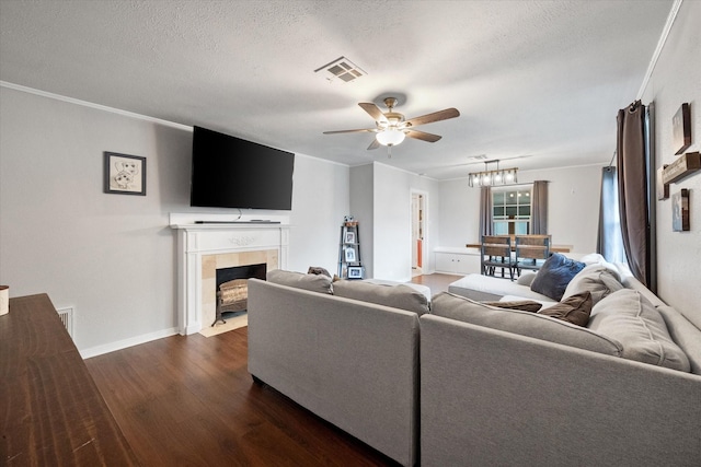 living room with a fireplace, dark hardwood / wood-style flooring, ornamental molding, ceiling fan, and a textured ceiling