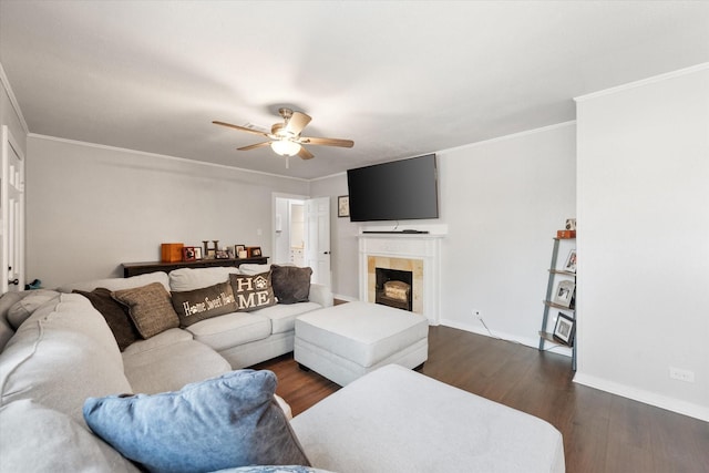 living room with dark hardwood / wood-style flooring, ornamental molding, a tile fireplace, and ceiling fan