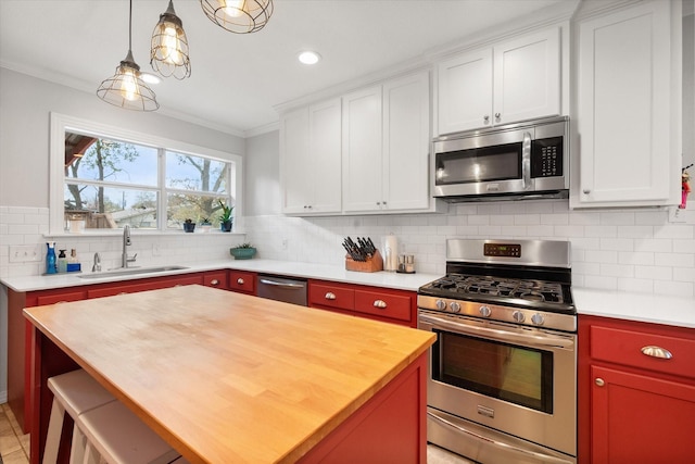 kitchen with sink, appliances with stainless steel finishes, white cabinetry, hanging light fixtures, and a center island