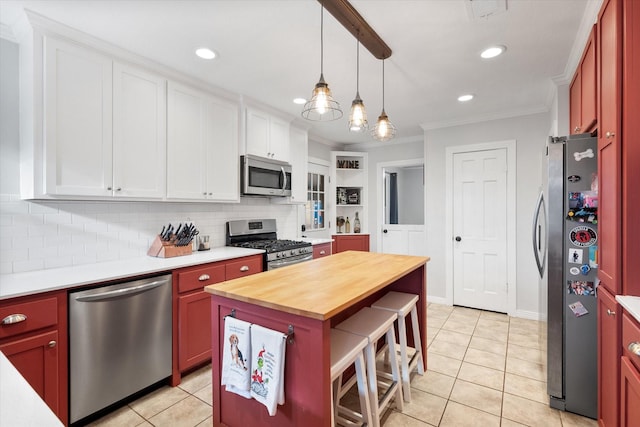 kitchen featuring wooden counters, appliances with stainless steel finishes, white cabinets, a kitchen island, and decorative light fixtures