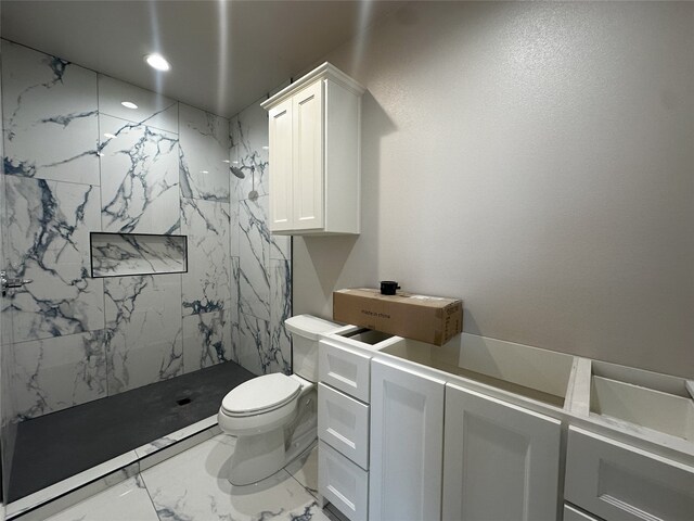 bathroom featuring toilet, vanity, and tiled shower