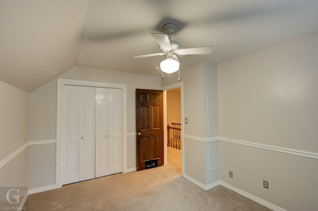 unfurnished bedroom featuring light carpet, a closet, ceiling fan, and lofted ceiling