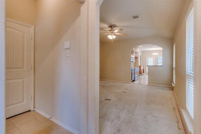 corridor with an inviting chandelier, lofted ceiling, and light tile patterned floors