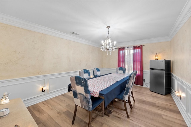 dining room with light hardwood / wood-style flooring, ornamental molding, and a chandelier