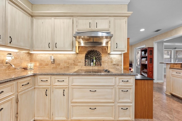 kitchen with tasteful backsplash, dark stone countertops, black electric stovetop, and light brown cabinets