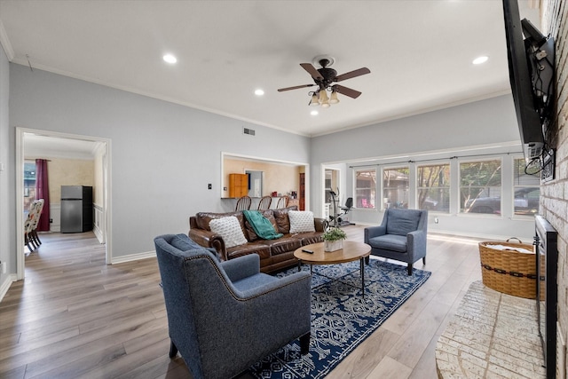 living room with ceiling fan, ornamental molding, light hardwood / wood-style floors, and a brick fireplace