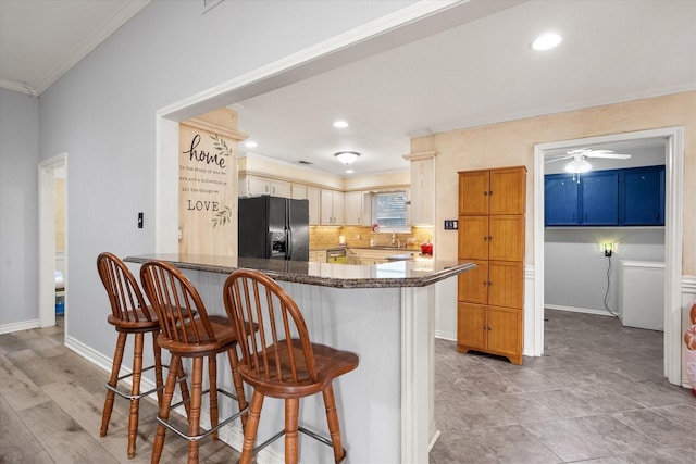 kitchen featuring backsplash, a kitchen breakfast bar, ornamental molding, black fridge with ice dispenser, and kitchen peninsula