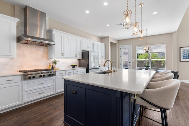 kitchen with dark wood-style floors, wall chimney exhaust hood, freestanding refrigerator, and a sink